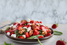Plate Of Homemade Fresh Salad Of Baby Spinach Leaves, Sliced Strawberries, Walnuts, Feta Cheese, And A Light Vinaigrette Dressing. Selective Focus With Extreme Shallow Depth Of Field.