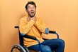 Handsome man with beard sitting on wheelchair shouting suffocate because painful strangle. health problem. asphyxiate and suicide concept.
