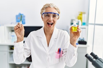 Sticker - Middle age blonde woman working at laboratory smiling and laughing hard out loud because funny crazy joke.