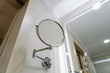 Closeup view photography of elegant round magnifying mirror attached to wall in bathroom interior