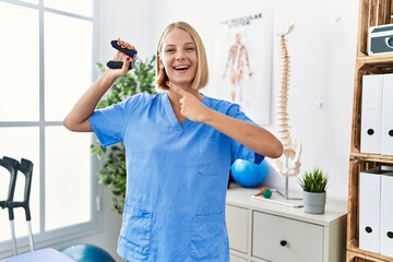 Sticker - Young caucasian physiotherapist woman holding hand grip to train muscle smiling happy pointing with hand and finger