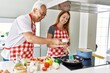© Krakenimages.com - Middle age hispanic couple smiling happy cooking at the kitchen.