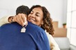 © Krakenimages.com - Middle age hispanic couple smiling happy and hugging. Standing with smile on face holding key of new home.
