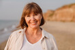 © Drobot Dean - Senior european woman smiling while walking on beach