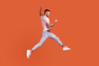 © khosrork - Side view portrait of happy bearded man jumping in air showing yes i did it gesture, copy space for ad, wearing pink T-shirt and jeans. Indoor studio shot isolated on orange background.