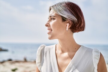 Sticker - Young caucasian girl smiling happy listening to music at the beach.