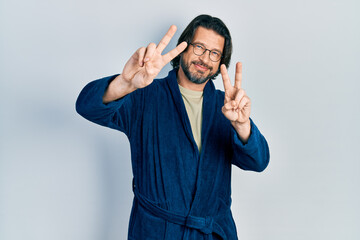 Canvas Print - Middle age caucasian man wearing bathrobe and glasses smiling looking to the camera showing fingers doing victory sign. number two.