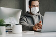 © Drobot Dean - Young man in protective mask working with laptop at office