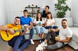 © Krakenimages.com - Group of young friends on party smiling happy and playing classical guitar at home.
