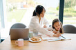 © Drobot Dean - Asian girl doing homework with her mother in kitchen