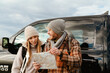 © Drobot Dean - White happy couple talking and examining paper map during car trip