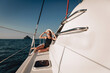 © Semachkovsky  - Portrait of a shining charismatic and young woman in a black bodysuit swimsuit, sunglasses and Panama, posing and sitting on a white road sailboat