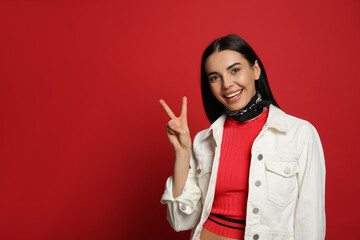 Wall Mural - Fashionable young woman in stylish outfit with bandana on red background