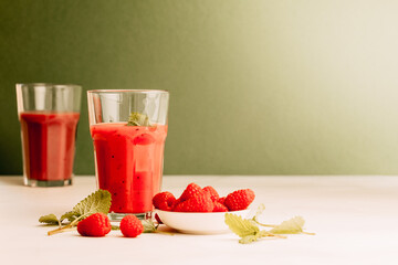 2 glasses with smoothie and drinking straws made of glass. Healthy eating and sustainability. Smoothie made from raspberries and other red fruits. Zero waste and reusable drinking straws made of glass