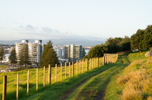 Track Around Mount Maunganui Along Fence-line With View Out To Buildings In Town And Ocean Beach, Tauranga