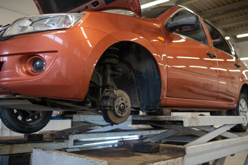 Wall Mural - Side part of broken car of light brown color without one wheel standing in workshop to get checked and repaired