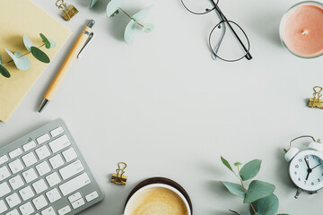 Wall Mural - Top view, flat lay keyboard, cup of coffee, paper notebook, pen eucalyptus branches on office desk table. Elegant feminine workspace.