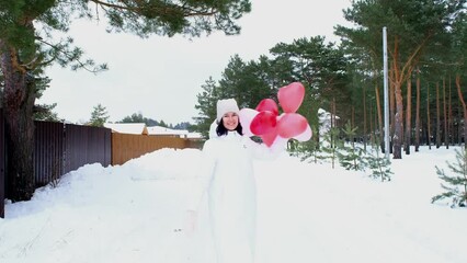 Wall Mural - Happy woman with heart-shaped balloons outdoor in winter with snow. Valentine's Day, love and infatuation, a gift from a boyfriend, a declaration of love, lifestyle. slow motion video 4k