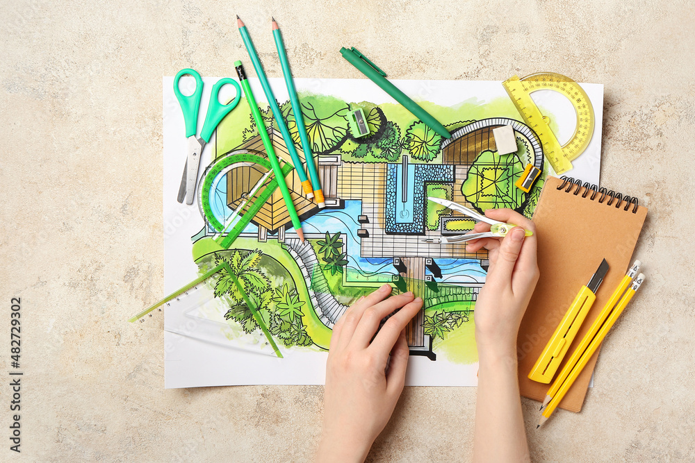 Landscape designer with pair of compasses and plan on grunge background