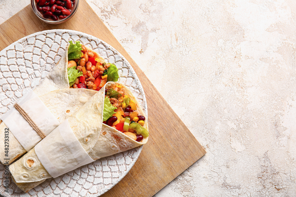 Plate with delicious burritos on light background
