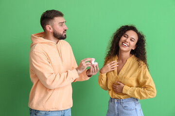 Wall Mural - Young African-American woman laughing and rejecting marriage proposal on color background