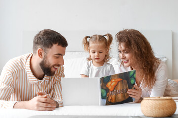 Wall Mural - Happy young family reading book in bedroom at home