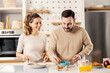 © dusanpetkovic1 - A couple in the kitchen at their cozy apartment preparing a meal together.