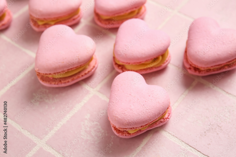 Tasty heart-shaped macaroons on pink background, closeup
