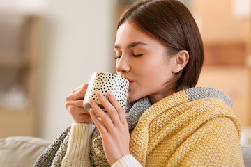 Wall Mural - Beautiful young woman drinking tasty tea on sofa at home