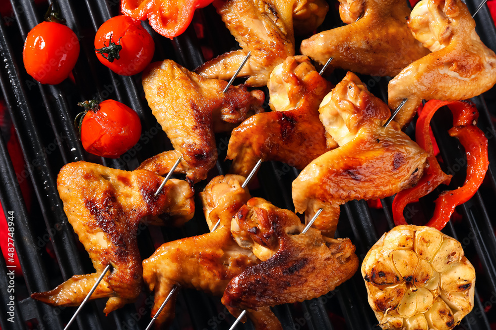 Tasty chicken wings skewers with vegetables on grill