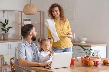 Canvas Print - Happy young family with laptop in kitchen at home