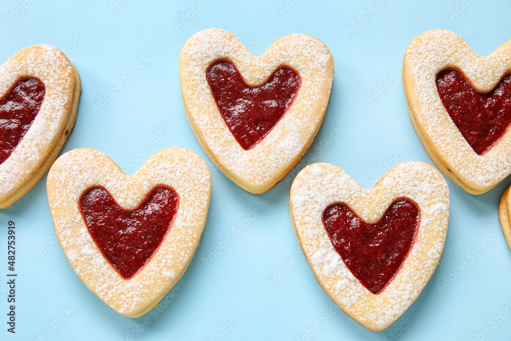 Tasty cookies in heart shape on blue background