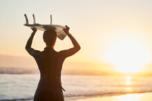 Surfing Is A Way Of Life. Rearview Shot Of A Female Surfer Carrying Her Surfboard Over Her Head At The Beach.