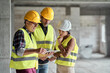 © gpointstudio - Three caucasian engineers discussing over digital tablet on the construction site
