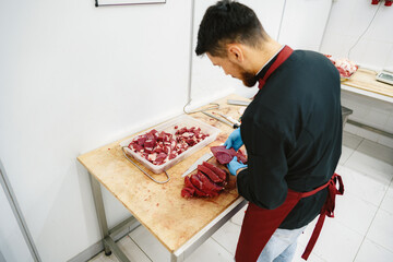 Wall Mural - Butcher cutting slices of raw meat on wooden board