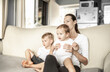 © kieferpix - Mother and her children at home sitting on couch sofa watching TV, videos