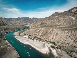 Top view on a long light turquoise river stretching along the sandy banks, dividing into two directions at the end of the river