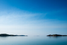 Glass Off Ocean With Islands In Distance, Horizon Blending Into Sky