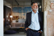 © opolja - Positive confident mature executive man smiling and looking away while standing in office