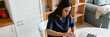 © Drobot Dean - Focused woman doctor opening her wallet and using laptop at home