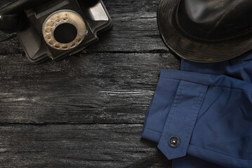 Wall Mural - Black wooden detective table flat lay concept background with copy space. Rotary phone and black leather hat on the desk.