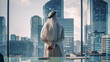 © Gorodenkoff - Successful Muslim Businessman in Traditional White Kandura Standing in His Modern Office Looking out of the Window on Big City with Skyscrapers. Successful Saudi, Emirati, Arab Businessman Concept.