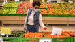 © emaria - Elderly woman in medical mask and eye glasses chooses and buys tomatoes in supermarket at pandemic time
