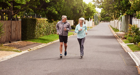 Poster - Try and keep up. Shot of a cheerful senior couple having a jog together outside in a suburb.