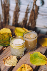 Wall Mural - A vertical shot of two glasses of hot mulled pear juice on the table covered in dried leaves