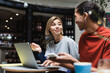 © LIGHTFIELD STUDIOS - Smiling freelancer talking to african american friend near devices in cafe.