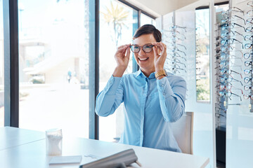 Poster - These glasses are spectacular. Shot of a young woman buying a new pair of glasses at an optometrist store.