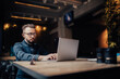 © velimir - man works on the Internet with a laptop in glasses in a coworking cafe, the concept of freelancer remote work.