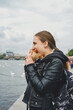 young woman eats burger at the fair outdoors on an embankmenkt Naplavka, Prague, Czech Republic
