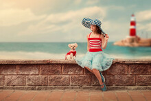 A Girl With A Poodle Dog Sits On The Background Of A Lighthouse By The Sea